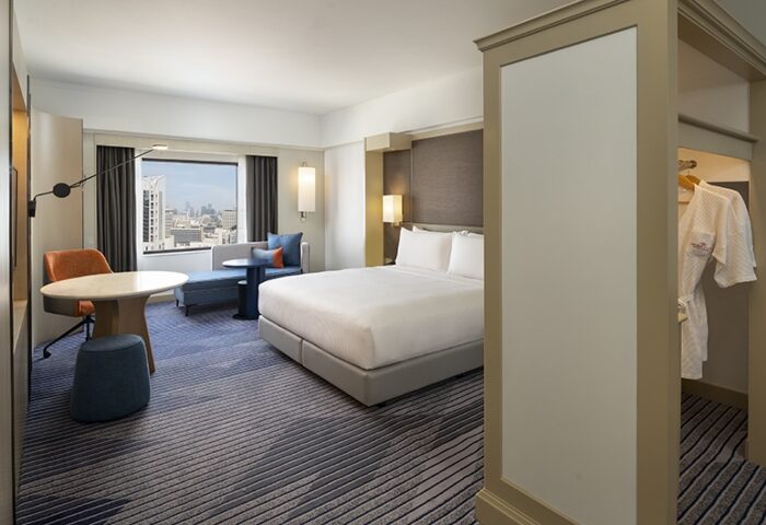 Gay honeymoon hotel room at Crowne Plaza Bangkok Lumpini Park. City view, bed, desk, and closet with robe. Bangkok city center hotel.