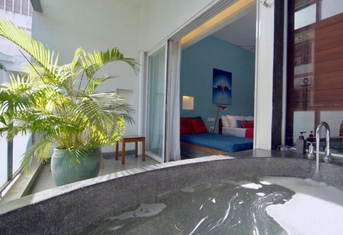 Rambutan Resort Phnom Penh: Cheap gay hotel room view with bathtub, balcony, and bed. A relaxing gay travel destination in Cambodia.