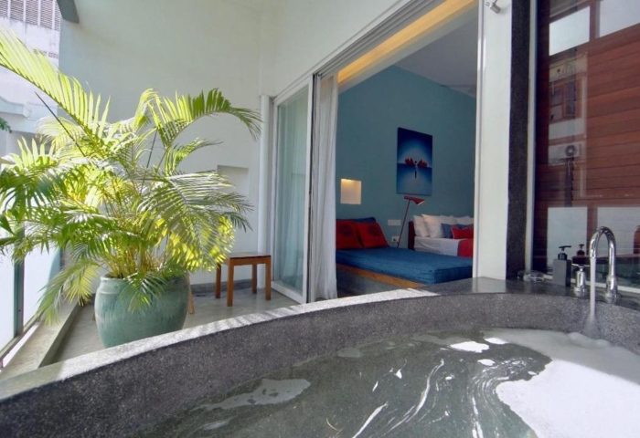 Rambutan Resort Phnom Penh: Cheap gay hotel room view with bathtub, balcony, and bed. A relaxing gay travel destination in Cambodia.