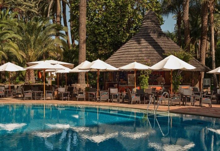 Seaside Palm Beach hotel pool, Gran Canaria. Gay beach hotel with bar, umbrellas, tables, and chairs. A relaxing gay travel destination.