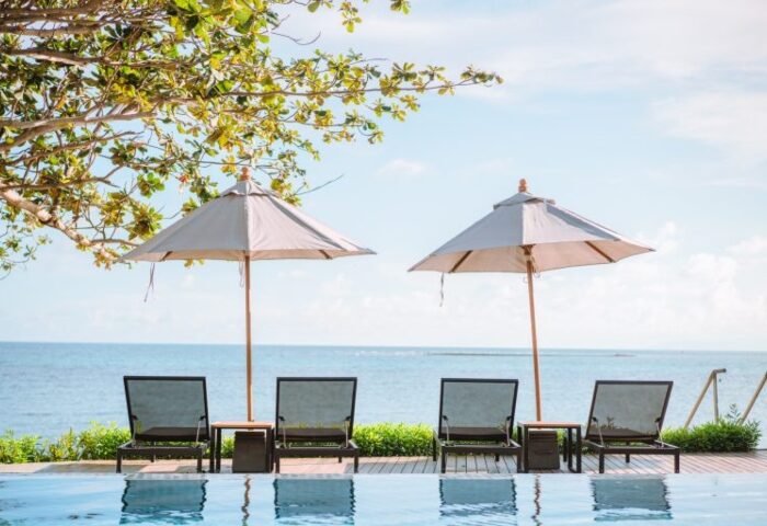 Rocky's Boutique Resort, Koh Samui. Beachfront view with lounge chairs and umbrellas by the pool. Gay honeymoon destination in Thailand.