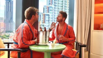 Gay Honeymoon at The Standard, Bangkok Mahanakhon. Two men in robes enjoy drinks with a city view. Luxury gay travel in Thailand.