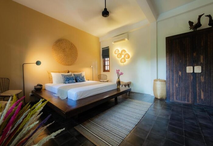 Bedroom at Rambutan Resort, Siem Reap. Honeymoon suite interior with king-size bed, wooden accents, and stylish decor. Gay-friendly hotel.