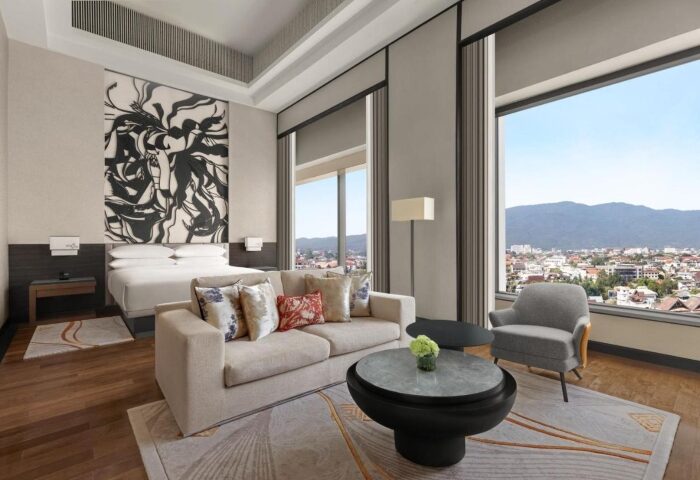 Chiang Mai Marriott Hotel suite. Gay honeymoon hotel room featuring a king bed, sofa, city view, and modern decor. Thailand travel.
