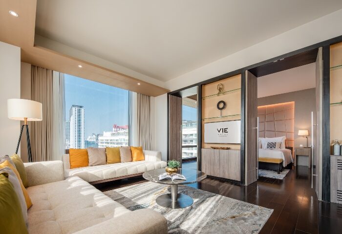 VIE Hotel Bangkok suite, gay honeymoon hotels. Modern living room with city view, leading to bedroom. Luxury gay travel in Bangkok.
