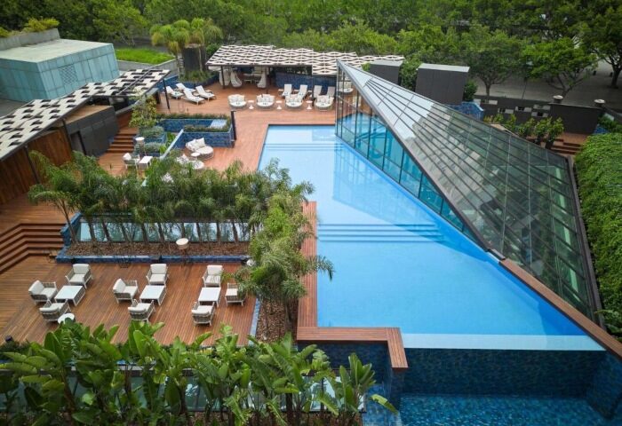 Sofitel Barcelona Skipper pool area, top gay hotel near Mar Bella gay beach. Modern design, poolside seating, and lush greenery.