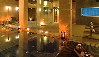 Axel Hotel Barcelona Urban Spa, gay adults only. Luxurious spa interior with pool, candles, and relaxing ambiance. Number one gay hotel.