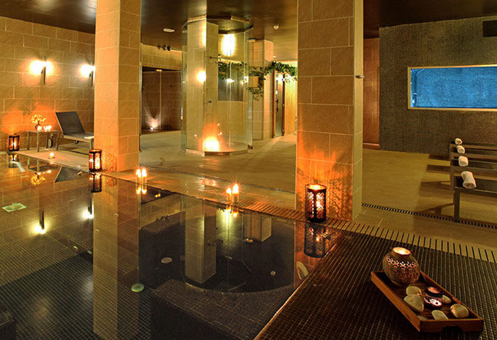 Axel Hotel Barcelona Urban Spa, gay adults only. Luxurious spa interior with pool, candles, and relaxing ambiance. Number one gay hotel.