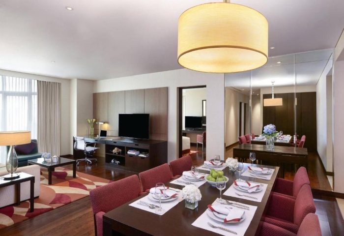 Sathorn Vista, Bangkok Marriott Executive Apartments living area. Ideal for gay groups. Modern interior, dining table, workspace, and TV.