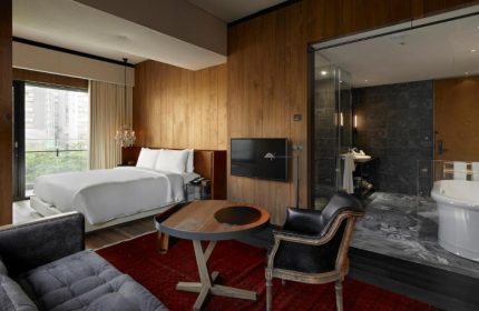 Hotel Proverbs Taipei room. One of Taipei's number one gay hotels for Taipei PRIDE. Bed, bath, chair, and table in a modern, stylish room.