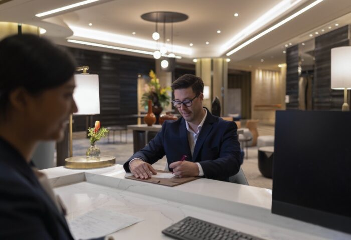 Crowne Plaza Bangkok Lumpini Park check-in. Man signing at reception. Gay-friendly hotel in Silom, near gay bars and saunas. Bangkok travel.