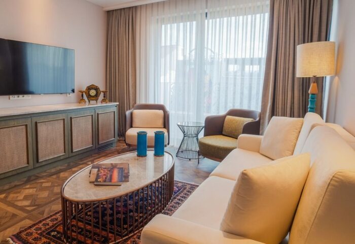 Burdock Hotel Istanbul, Autograph Collection room. Gay-friendly hotel living area with sofa, chairs, TV, cabinet, and coffee table. Stylish decor.