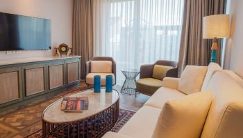 Burdock Hotel Istanbul, Autograph Collection room. Gay-friendly hotel living area with sofa, chairs, TV, cabinet, and coffee table. Stylish decor.