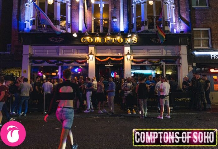 Comptons of Soho, London's gay street bar. A crowd gathers outside the popular pub, decorated with rainbow flags. Nightlife scene.