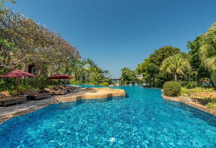 InterContinental Pattaya Resort pool view. Luxury beachfront hotels for gay men. Tropical landscape, blue water, and lounge chairs.
