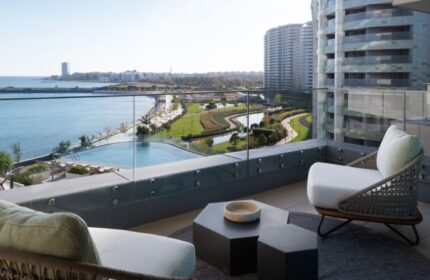 JW Marriott Hotel Istanbul Marmara Sea balcony view. Luxury gay honeymoon beachfront hotel. Chairs, tables, sea, and city skyline.