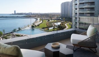 JW Marriott Hotel Istanbul Marmara Sea balcony view. Luxury gay honeymoon beachfront hotel. Chairs, tables, sea, and city skyline.