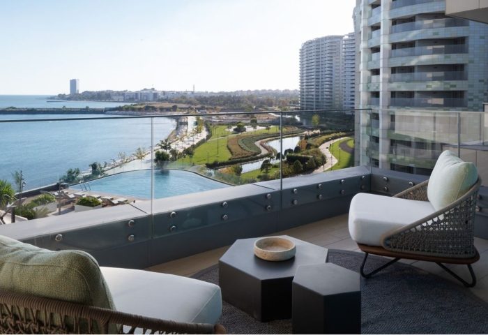 JW Marriott Hotel Istanbul Marmara Sea balcony view. Luxury gay honeymoon beachfront hotel. Chairs, tables, sea, and city skyline.