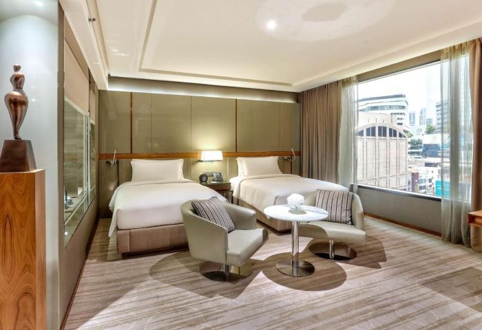 Hilton Sukhumvit Bangkok, gay-friendly hotel room. Two beds, chairs, table, and city view. Popular choice for gay travelers.