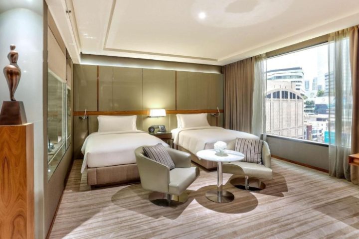 Hilton Sukhumvit Bangkok, gay-friendly hotel room. Two beds, chairs, table, and city view. Popular choice for gay travelers.