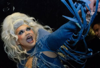 Drag queen performing at a gay bar in Vancouver. Best nightlife in gay Vancouver. Travel guide. Denim dress with blue laces. Blonde wig.