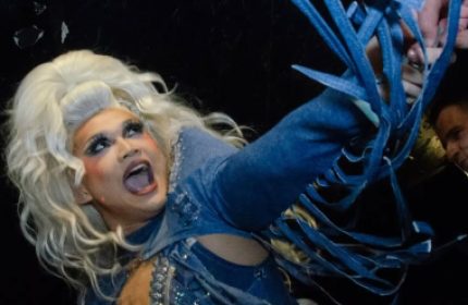 Drag queen performing at a gay bar in Vancouver. Best nightlife in gay Vancouver. Travel guide. Denim dress with blue laces. Blonde wig.