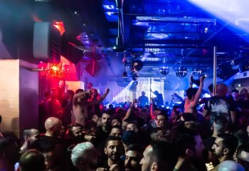 Crowded dance floor at ONEWAY Discoclub in Milan. Gay men enjoy the vibrant nightlife with disco balls and colorful lighting. Party atmosphere.