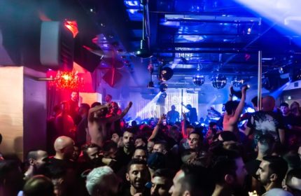 Crowded dance floor at ONEWAY Discoclub in Milan. Gay men enjoy the vibrant nightlife with disco balls and colorful lighting. Party atmosphere.