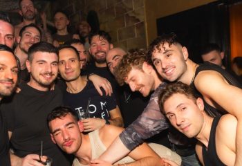 Gay men gather at ONEWAY Discoclub in Milan. Nightlife scene with smiling men, some shirtless, enjoying a night out. Gay travel advice.