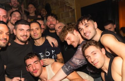 Gay men gather at ONEWAY Discoclub in Milan. Nightlife scene with smiling men, some shirtless, enjoying a night out. Gay travel advice.