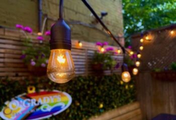 O'Grady's On Church bar in Toronto, a gay-friendly travel destination. String lights illuminate the outdoor patio, with flowers and greenery.