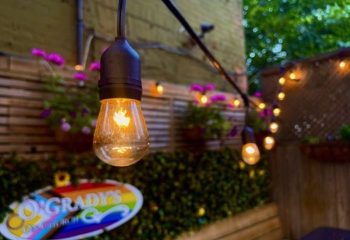 O'Grady's On Church bar in Toronto, a gay-friendly travel destination. String lights illuminate the outdoor patio, with flowers and greenery.