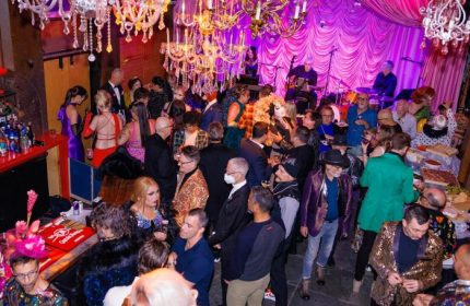 Oasis Drag Cabaret in San Francisco: A vibrant, crowded scene with drag queens, a live band, and patrons enjoying the lively atmosphere.