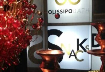 Olissipo Bath Lisbon detail. Red and gold baubles, copper candle holders, and illuminated signage. Gay travel advice for Lisbon.