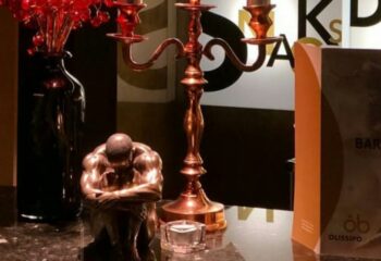 Olissipo Bath Lisbon decor: Bronze male statue, candle holder, vase with red flowers. Gay travel guide to Lisbon bathhouses.