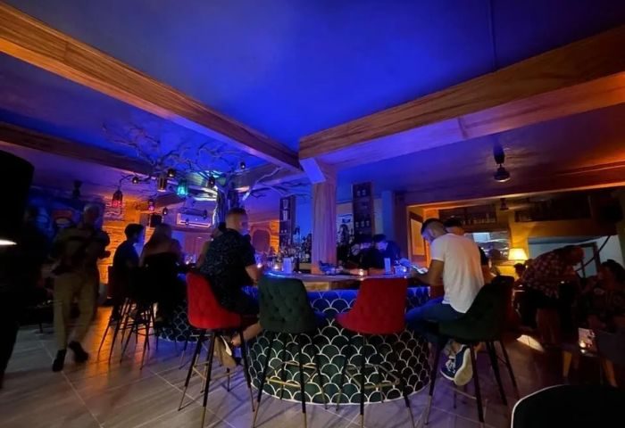 Interior of One Six One, a gay bar in Puerto Vallarta, featuring patrons at the bar, blue lighting, and unique decor.