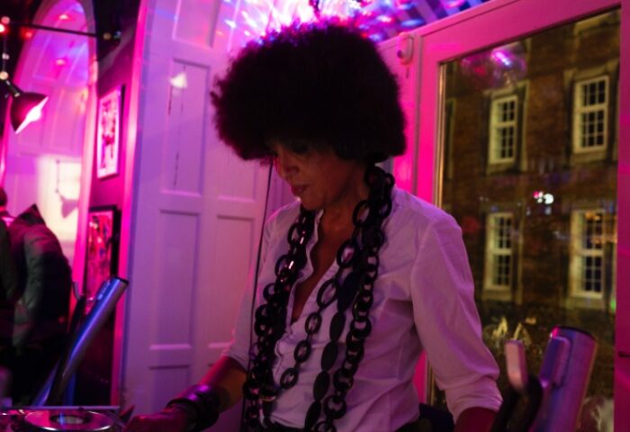 DJ at Oscar Bar Cafe in Copenhagen. Gay bar scene with DJ, afro, and pink lighting. Nightlife for gay men travel advice.