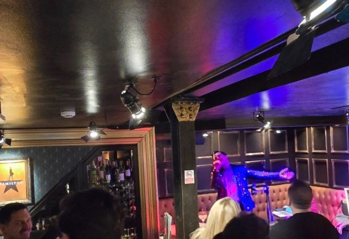 Singer performing at Oscars Bar Manchester, a gay venue, with stage lighting and an audience. Gay travel advice for nightlife.