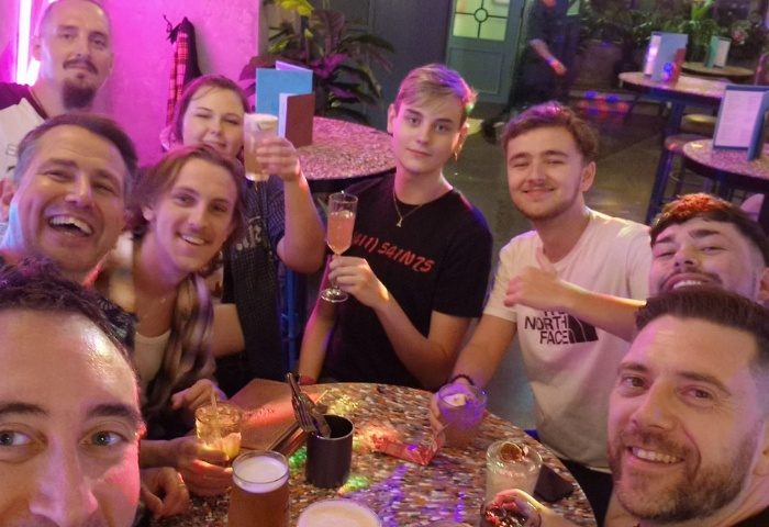 Group of friends at Oscars Bar Manchester. Gay travel destination, enjoying drinks. Nightlife scene. Celebrating with cocktails and beer.