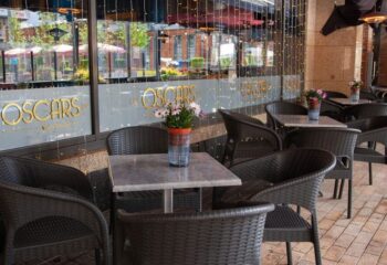 Oscar's Cafe Bar Dublin outdoor seating. Wicker chairs surround tables with flowers. Gay-friendly spot for drinks and socializing in Dublin, Ireland.