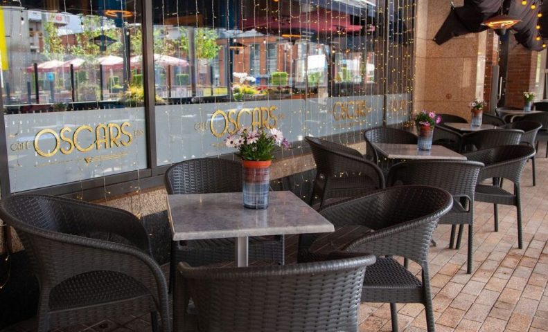 Oscar's Cafe Bar Dublin outdoor seating. Wicker chairs surround tables with flowers. Gay-friendly spot for drinks and socializing in Dublin, Ireland.