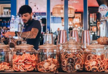 Oscar's Cafe Bar Dublin: Bartender preparing drinks. Jars of dried citrus fruit are on the bar. Popular gay bar in Dublin, Ireland.
