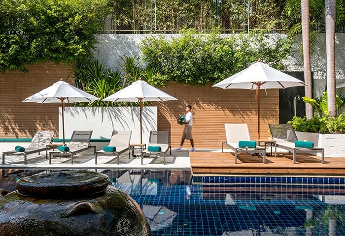 Outrigger Surin Beach Resort pool in Phuket, Thailand. Loungers and umbrellas provide poolside relaxation at this top gay hotel.