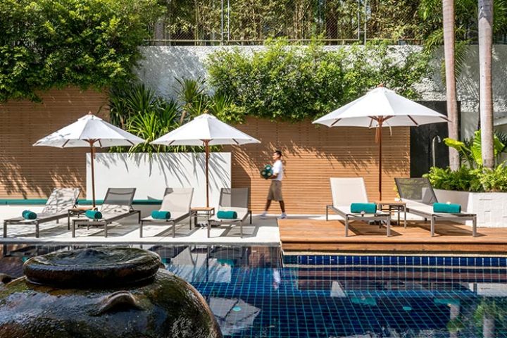 Outrigger Surin Beach Resort pool in Phuket, Thailand. Loungers and umbrellas provide poolside relaxation at this top gay hotel.