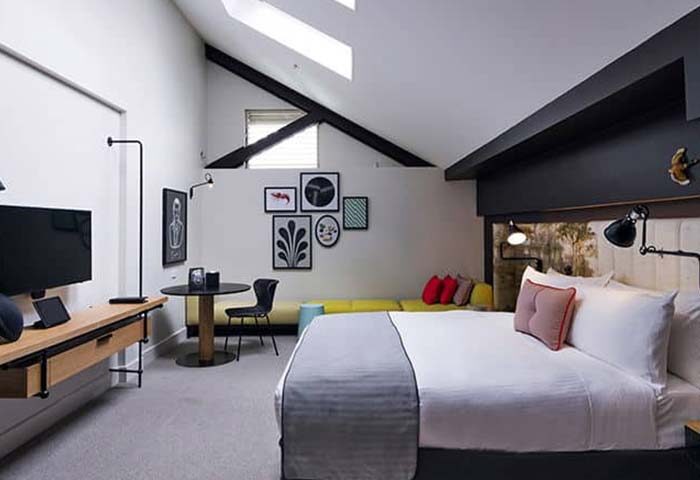Ovolo Woolloomooloo Luxe Hotel in Sydney, Australia. Modern room interior. Gay travel advice for a comfortable stay. Hotel room with bed.