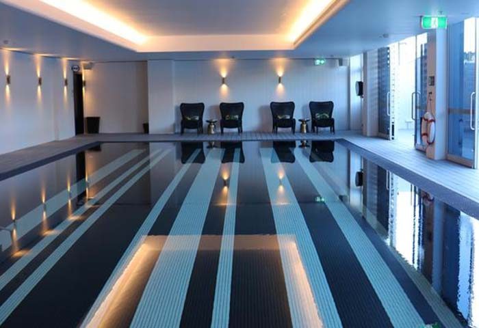 Ovolo Woolloomooloo Hotel Sydney pool. Indoor pool with striped floor, chairs, and soft lighting. Gay-friendly hotel for gay travel.