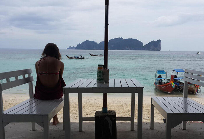 P.P. Blue Sky Resort beachfront view. Woman gazes at Phi Phi island from a table at this cheap gay hotel in Ton Sai, Thailand.