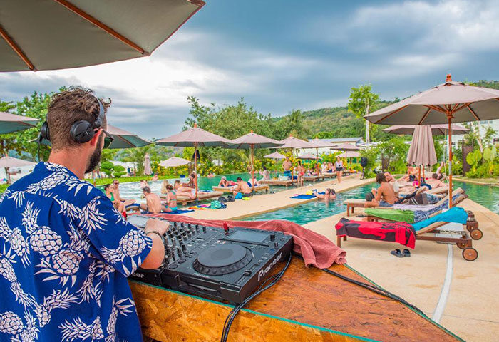 DJ spinning tunes at PP Charlie Beach Resort, Phi Phi. Gay-friendly hotel pool scene with sunbathers and tropical vibes. Cheap gay hotel.
