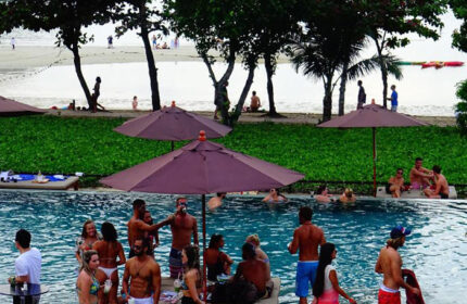 PP Charlie Beach Resort pool party. Gay beachfront hotel in Phi Phi Island, Thailand. People enjoying the pool, beach view.