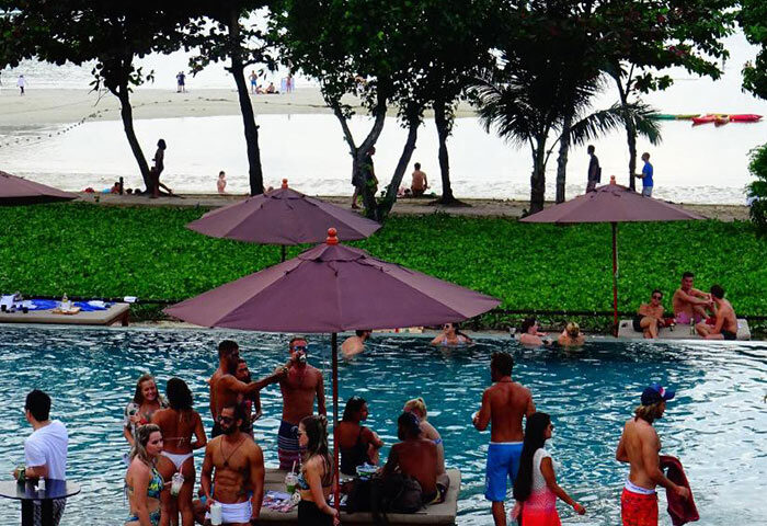 PP Charlie Beach Resort pool party. Gay beachfront hotel in Phi Phi Island, Thailand. People enjoying the pool, beach view.